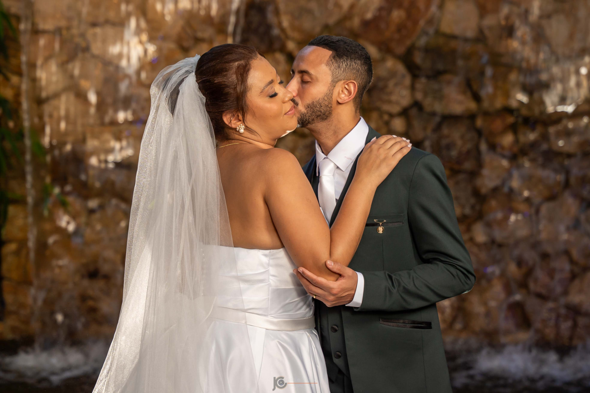 Casal se beijando em frente à cachoeira